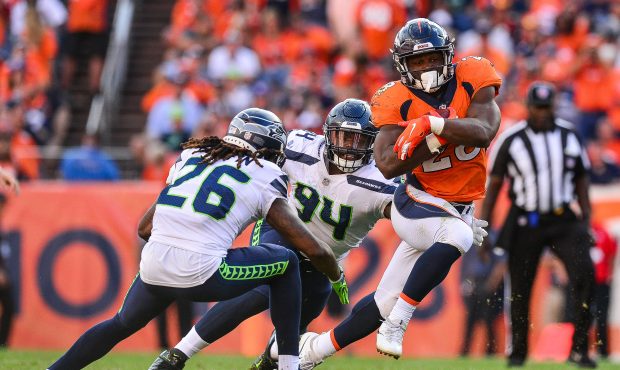 Running back Royce Freeman #28 of the Denver Broncos carries the ball and tries to avoid a tackle a...