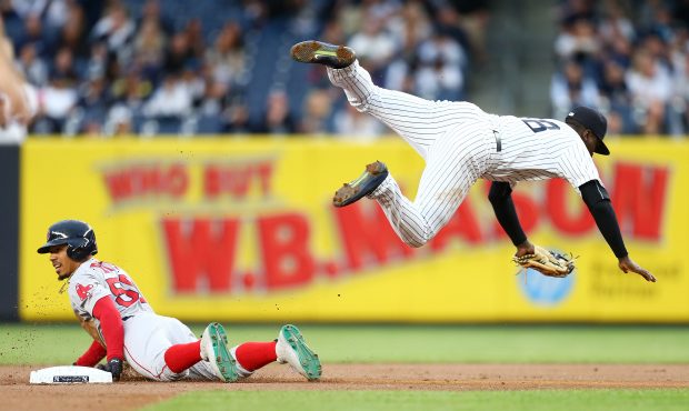 Didi Gregorius #18 of the New York Yankees is tripped up after tagging out Mookie Betts #50 of the ...