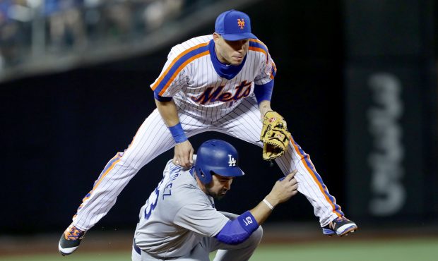 Asdrubal Cabrera #13 of the New York Mets jumps over Adrian Gonzalez #23 of the Los Angeles Dodgers...