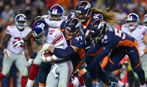 DENVER, CO - OCTOBER 15:  Quarterback Eli Manning #10 of the New York Giants is sacked by defensive...