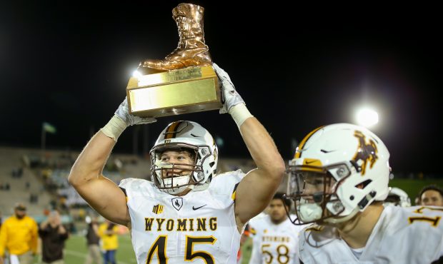 Linebacker Lucas Wacha #45 of the Wyoming Cowboys celebrates with The Bronze Boot after winning the...