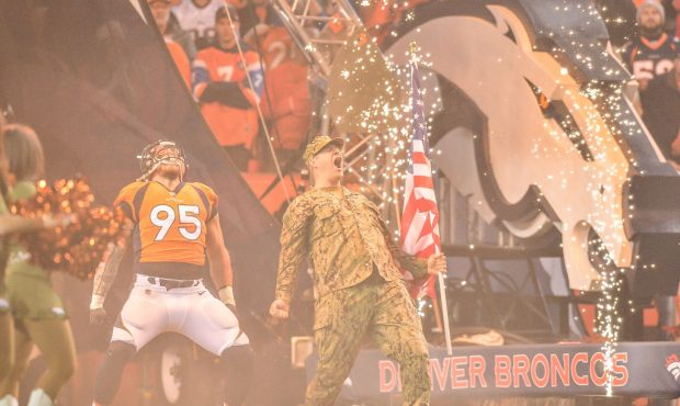 Defensive end Derek Wolfe #95 of the Denver Broncos yells with a member of the armed forces during ...