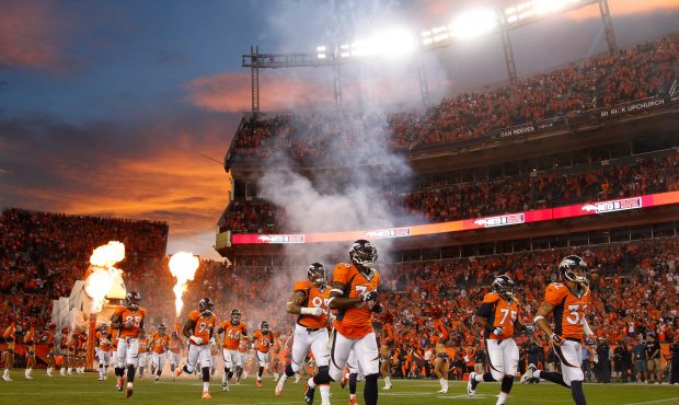 Denver Broncos defensive players run onto the field to a sunset and pyrotechnics during player intr...