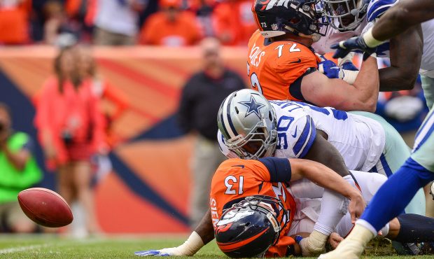 Quarterback Trevor Siemian #13 of the Denver Broncos is sacked by defensive end DeMarcus Lawrence #...
