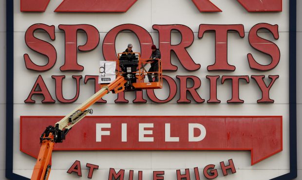 Crews, with Ad Light, work on disconnecting electrical wires to signage at Sports Authority Field a...