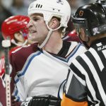 Defenseman Adam Foote #52 of the Colorado Avalanche is restrained by officials in game four of the Western Conference finals during the Stanley Cup playoffs against the Detroit Red Wings at the Pepsi Center in Denver, Colorado on May 25, 2002.  The Avalanche won the game 3-2 to tie the series 2-2.  (Photo by Brian Bahr/Getty Images/NHLI)