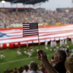 COMMERCE CITY, CO - JULY 4: A Colorado Rapids fan holds up an American flag during the singing of the national anthem before a game against the Vancouver Whitecaps FC at Dick's Sporting Goods Park July 4, 2012 in Commerce City, Colorado. (Photo by Marc Piscotty/Getty Images)