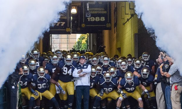 Notre Dame Fighting Irish head coach Brian Kelly runs out onto the field with his players in action...