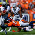 DENVER, CO - SEPTEMBER 16:  Running back Marshawn Lynch #24 of the Oakland Raiders is hit by defensive back Darian Stewart #26 of the Denver Broncos during the first quarter of a game at Broncos Stadium at Mile High on September 16, 2018 in Denver, Colorado. (Photo by Justin Edmonds/Getty Images)