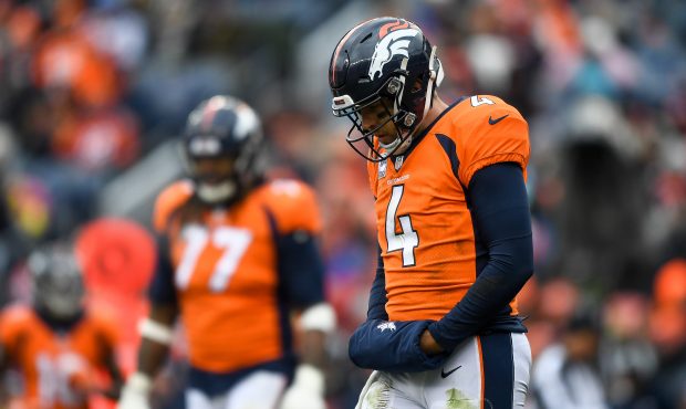 Quarterback Case Keenum #4 of the Denver Broncos hangs his head as he walks on the field in the thi...
