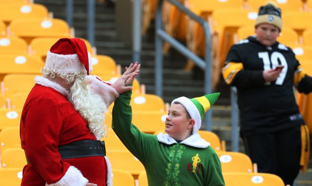An early arriving Santa Claus and elf high-five each other in the stands. The New England Patriots ...