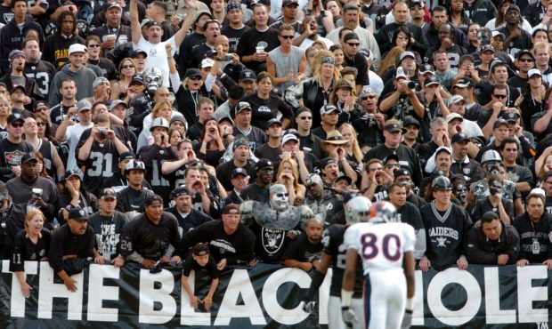 Fans in the black hole cheer as Rod Smith #80 of the Denver Broncos and Charles Woodson #24 of the ...