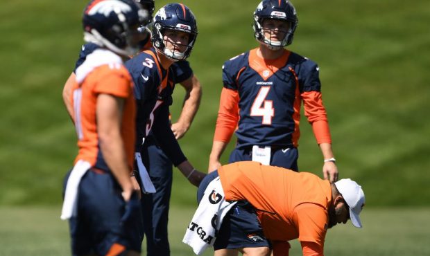 Denver Broncos quarterback Drew Lock #3 looks to his receiver as quarterback Brett Rypien #4 watche...