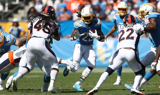 Melvin Gordon #25 of the Los Angeles Chargers runs the ball as Kareem Jackson #22 and Alexander Joh...
