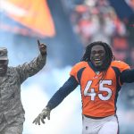 DENVER, CO - NOVEMBER 3:  A.J. Johnson #45 of the Denver Broncos carries the U.S. flag onto the field next to a service member in recognition of Veteran's Day during player introductions before a game against the Cleveland Browns at Empower Field at Mile High on November 3, 2019 in Denver, Colorado.  (Photo by Dustin Bradford/Getty Images)