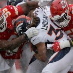 KANSAS CITY, MISSOURI - DECEMBER 15: Phillip Lindsay #30 of the Denver Broncos is tackled by Chris Jones #95 and Frank Clark #55 of the Kansas City Chiefs in the game at Arrowhead Stadium on December 15, 2019 in Kansas City, Missouri. (Photo by David Eulitt/Getty Images)