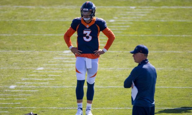 Quarterback Drew Lock #3 of the Denver Broncos stands on the field as Offensive Coordinator Pat Shu...