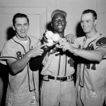 The long-ball hitters who contributed to Milwaukee's 13-hit attack against the Brooklyn Dodgers at Ebbets Field tonight are shown in the Braves' dressing room following the game. Johnny Logan (l) accounted for two hits, including a homer; Hank Aaron, who is holding three balls, accounted for four hits, including a homer and Eddie Mathews (r) hit a homer. The Braves dropped the Dodgers to fourth place in the National League by defeating them 7 to 3.
