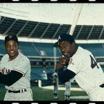 Willie Mays, (L) of the San Francisco Giants baseball team and Hank Aaron, (R) of Atlanta pose in uniforms here at a stadium. (Photo by Bettmann/Corbis/Getty Images)