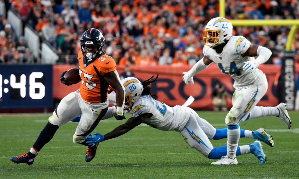 DENVER, CO - NOVEMBER 28: Denver Broncos Running Back Javonte Williams (33) slips the tackle of Los...