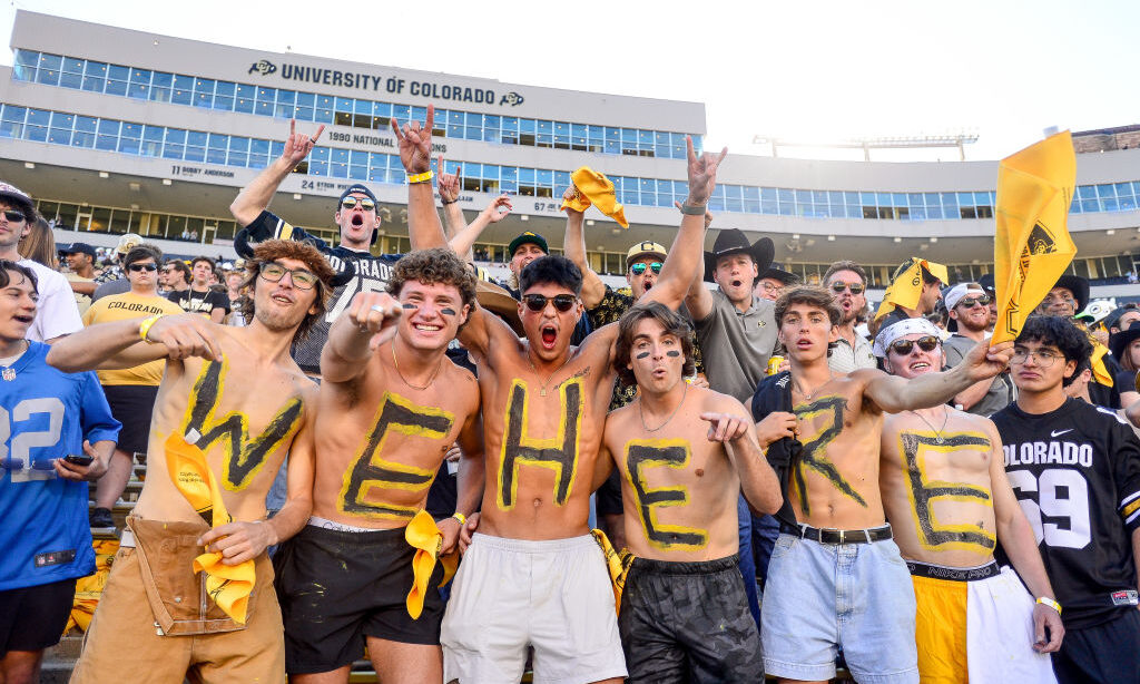 Colorado Buffaloes fans wear paint reading "We Here" as they cheer from the student section...