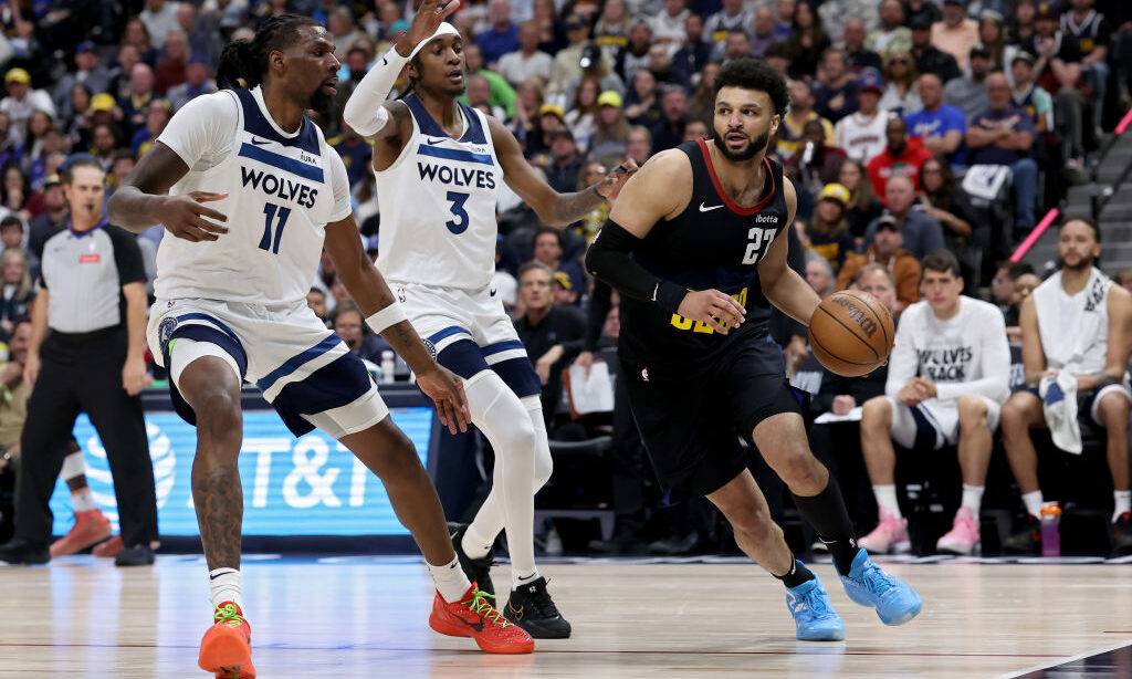 Jamal Murray of the Denver Nuggets drives past Naz Reid #11 and Jaden McDaniels #3 of the Minnesota...