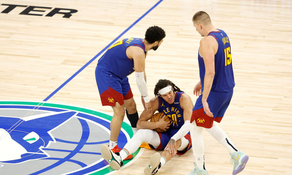 Aaron Gordon #50 of the Denver Nuggets is helped up by teammates Jamal Murray #27 and Nikola Jokic ...