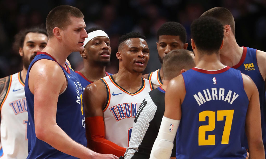 Russell Westbrook #0 of the Oklahoma Thunder is restrained by referee John Goble #30 from Jamal Mur...