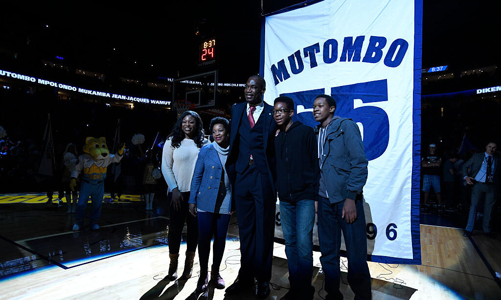 Former Denver Nuggets star Dikembe Mutombo poses with his family in front of his banner during his ...