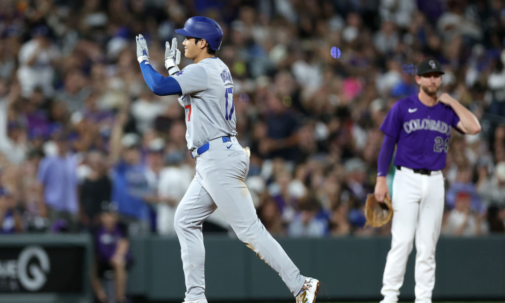 Shohei Ohtani #17 of the Los Angels Dodgers gestures as he circles the bases after hitting a three ...