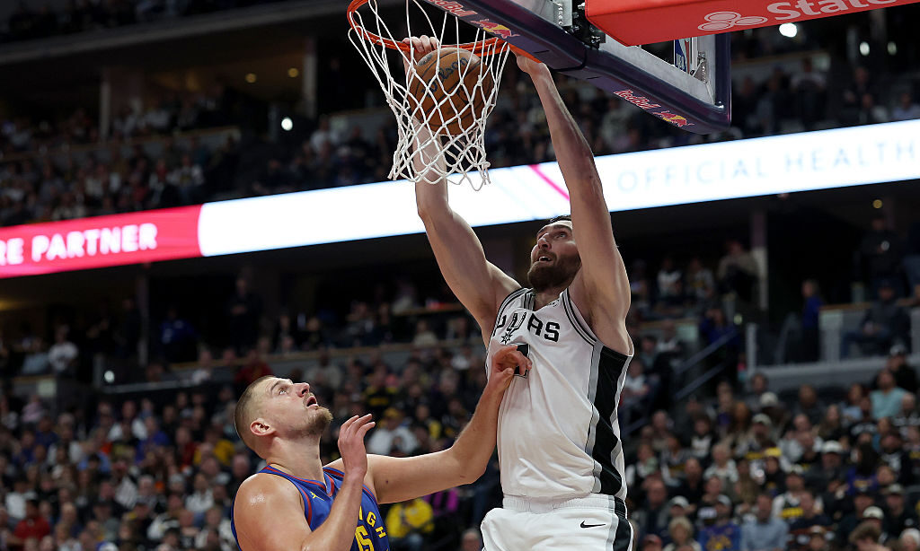 DENVER, COLORADO - NOVEMBER 28: Luke Kornet #7 of the San Antonio Spurs dunks on Nikola Jokic #15 o...