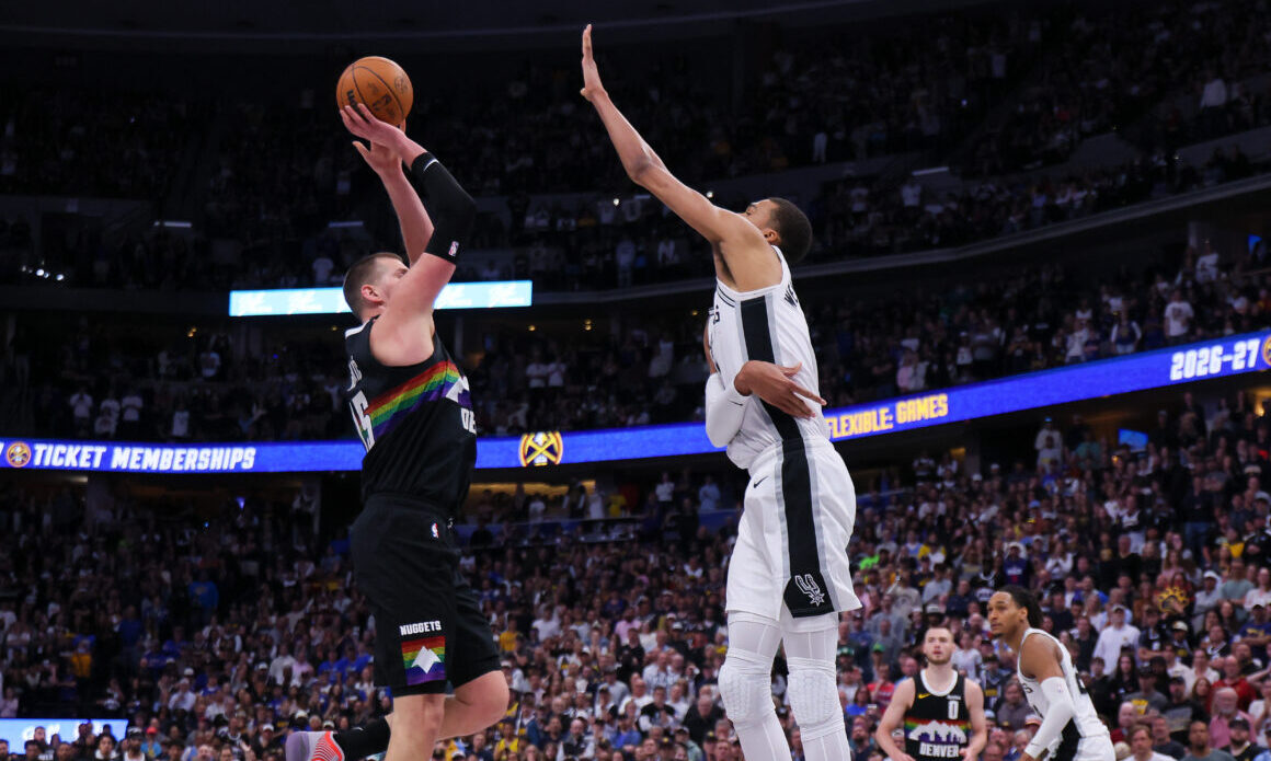 DENVER, CO - APRIL 4: Nikola Jokic #15 of the Denver Nuggets scores against Victor Wembanyama #1 of...