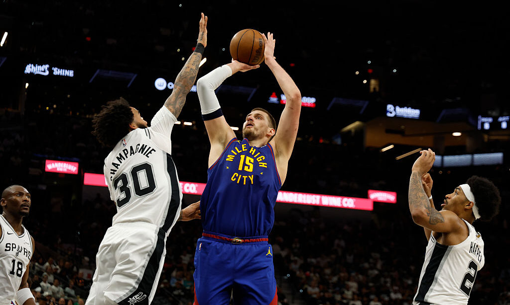 SAN ANTONIO, TX -APRIL 12: Nikola Jokic #15 of the Denver Nuggets shoots over Julian Champagnie #30...