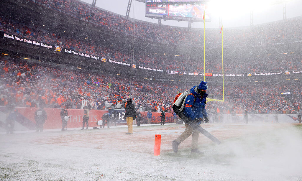 DENVER, COLORADO - JANUARY 25: Crew members clear the field of snow during the fourth quarter in th...