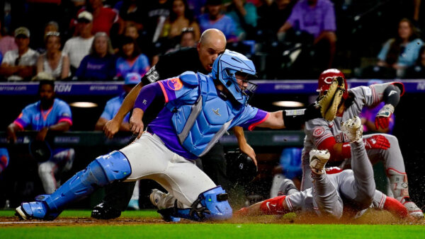 Spencer Steer of the Reds slides past Rockies Catcher Hunter Goodman with an inside-the-park home run