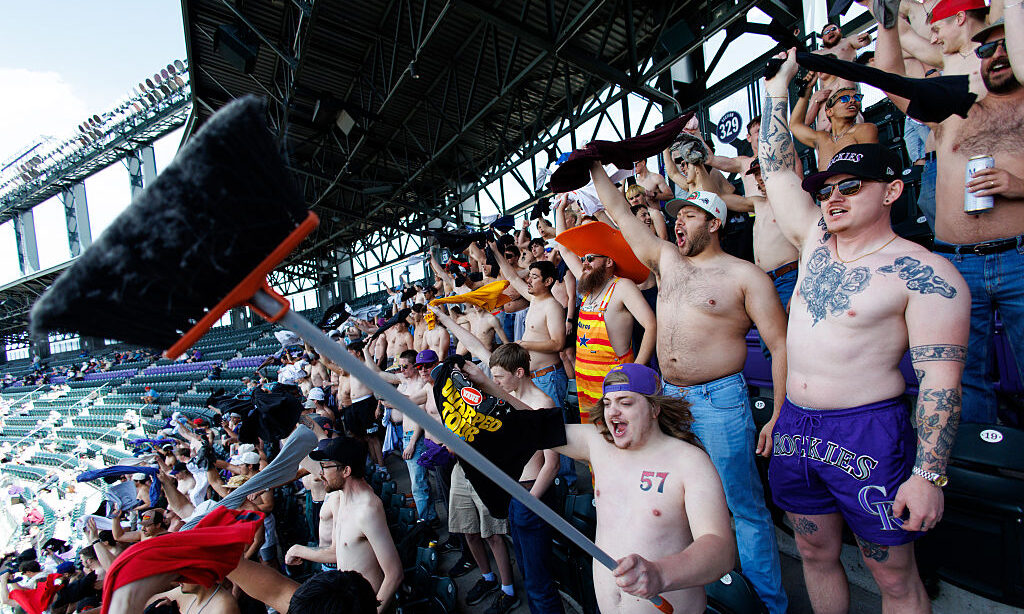 DENVER, CO - APRIL 8: A fan holds up a broom among a large group of shirtless fans cheering on the ...